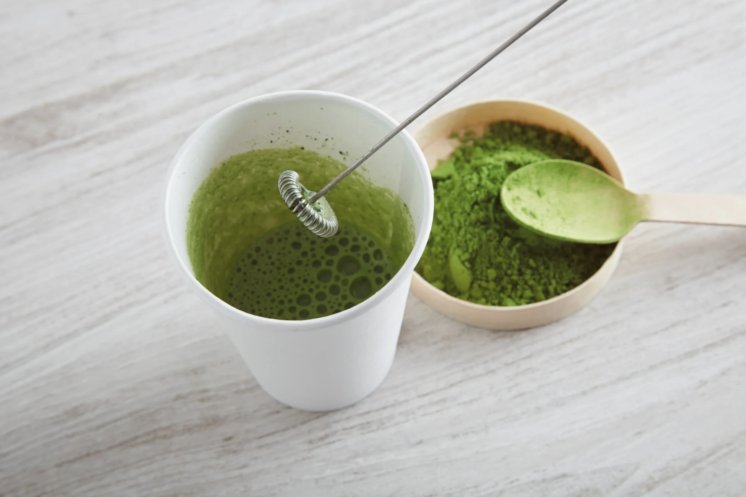 Preparación de bebida con alga espirulina en polvo dentro de un vaso blanco