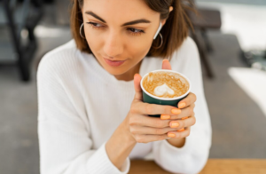 Mujer sosteniendo un vaso de café keto en una cafetería al aire libre