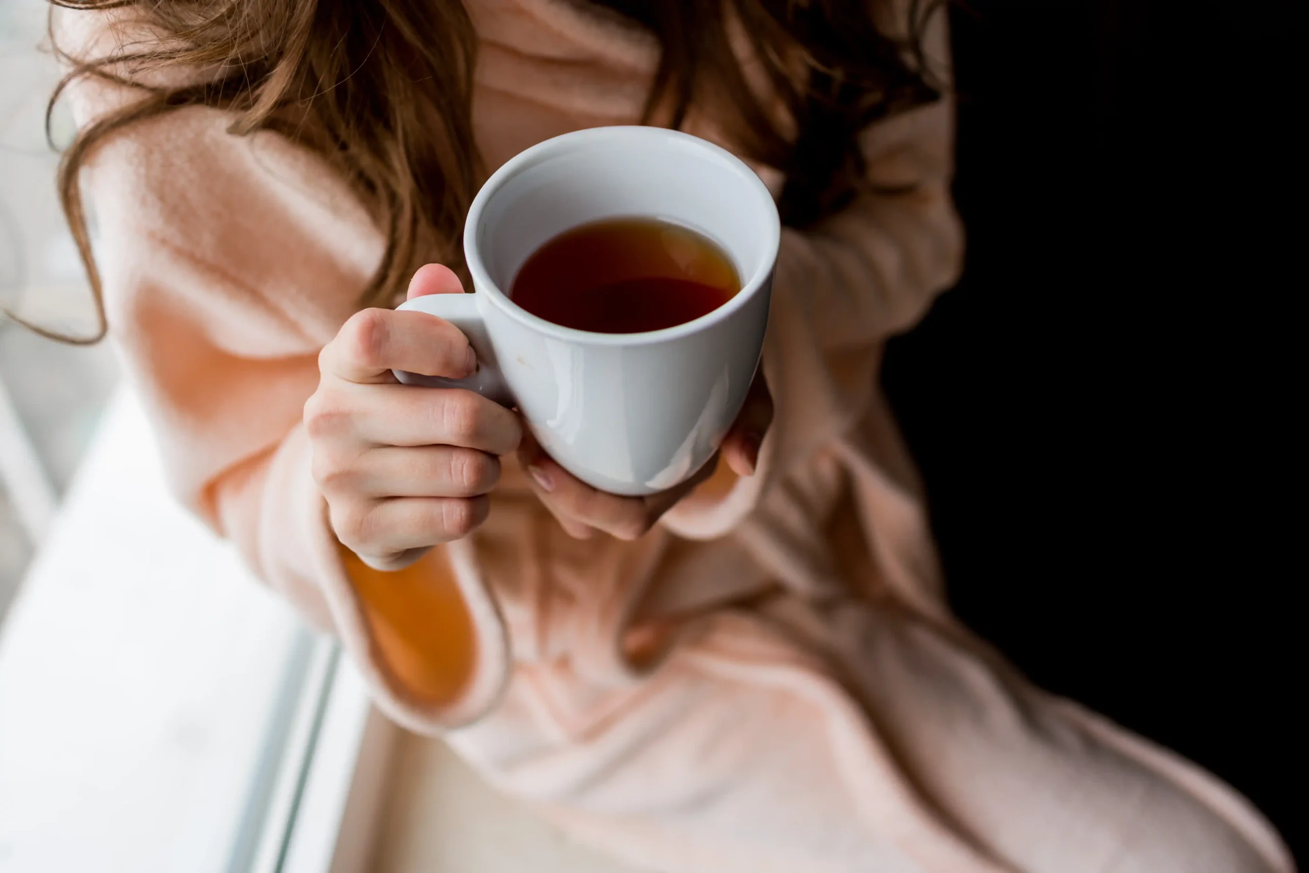 Mujer sosteniendo una taza de té para cólicos menstruales durante el periodo
