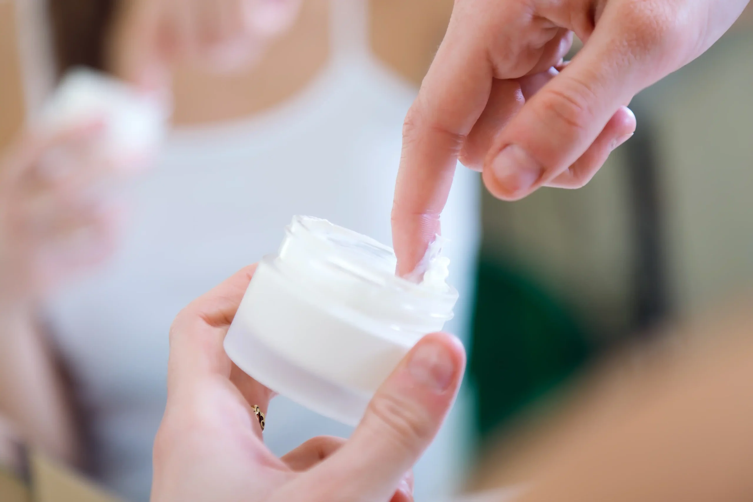 Persona con envase crema con ácido glicólico lista para aplicarla en el rostro