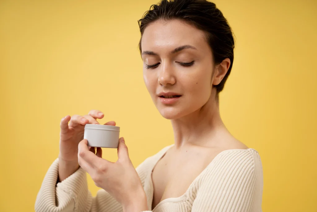 Mujer sosteniendo un frasco de crema con ácido glicólico, observando el producto antes de usarlo