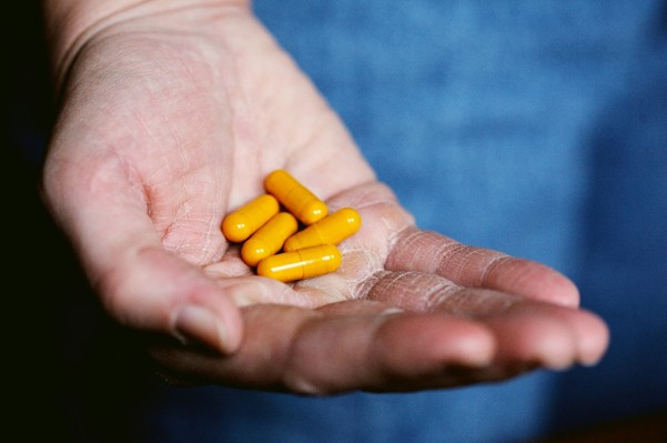 Persona sostiene cápsulas amarillas en la palma, ejemplo visual del consumo diario de polivitaminas y minerales