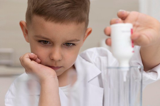 Un niño vertiendo gotas de vitamina ACD para tomarlas antes de su comida