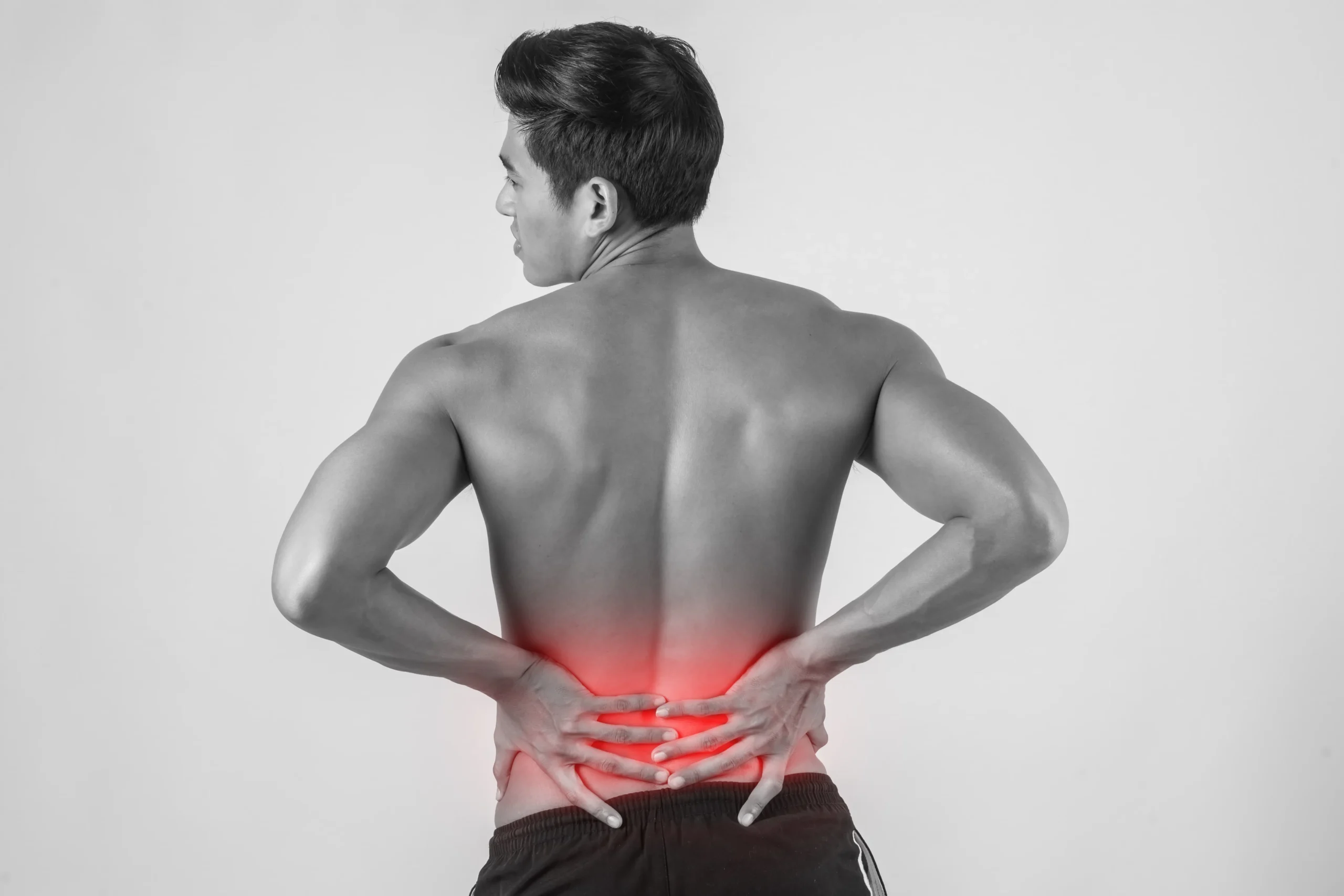 Hombre con dolor en la parte baja de la espalda que sostiene su zona lumbar, representando dolor muscular y articular