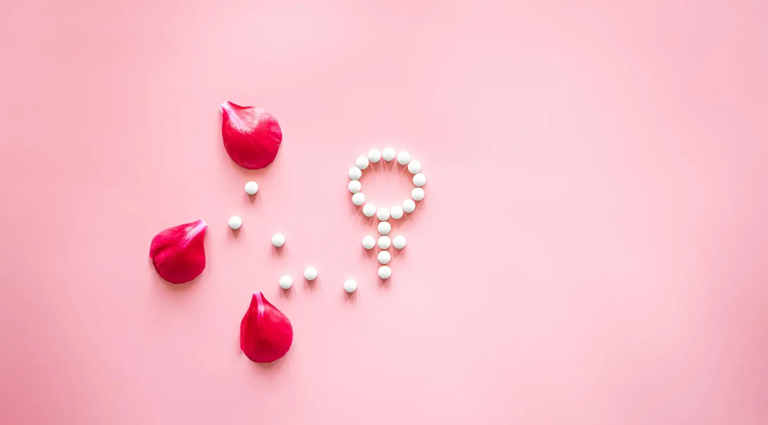 Símbolo de Venus de género hecho de pastillas y pétalos de flores de peonía sobre un fondo rosa